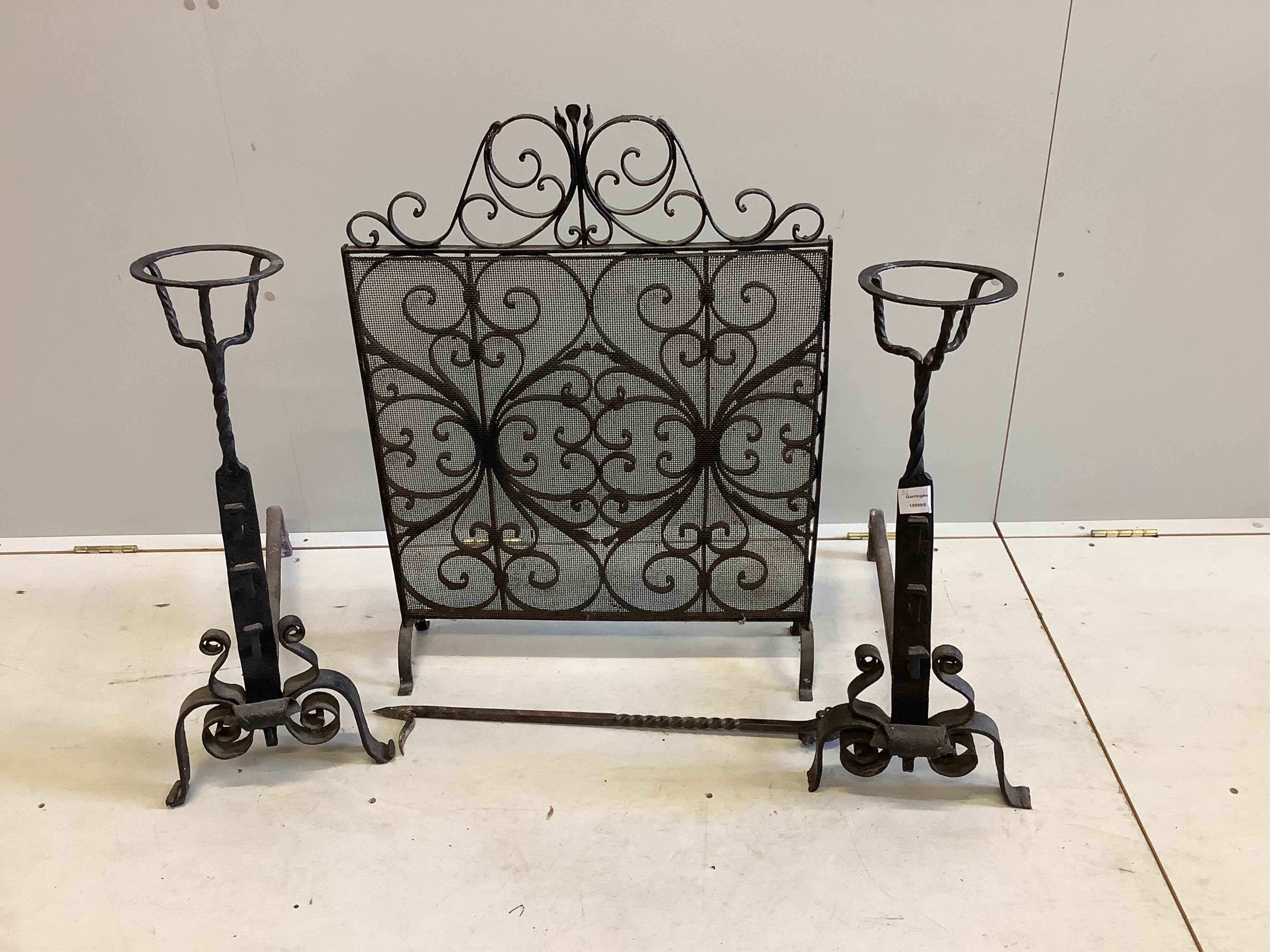 A pair of wrought iron fire dogs, with brazier finials, height 71cm, a wrought iron and wire mesh spark guard and a poker. Condition - fair